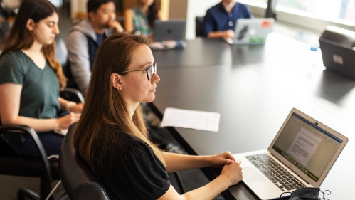 A group of students sits around a table in a classroom environment