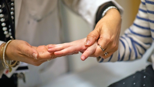 An adult physician holds a child's hand
